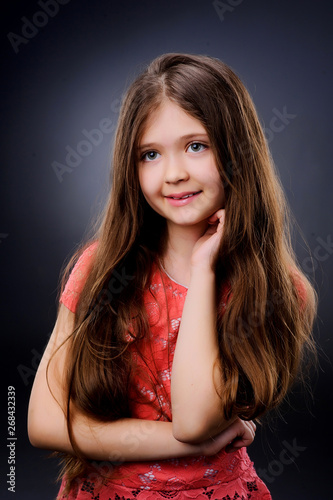Studio portrait of a girl 6-7 years old .Cute little girl posing in studio on dark background.