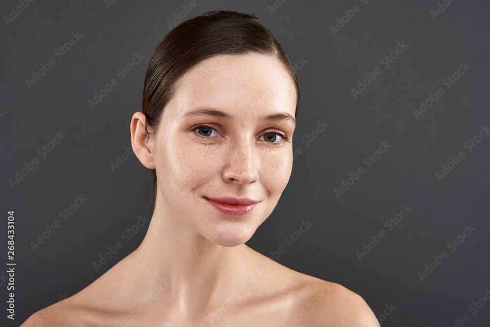 Charming girl with freckles standing against gray background Charming girl with freckles standing against gray background