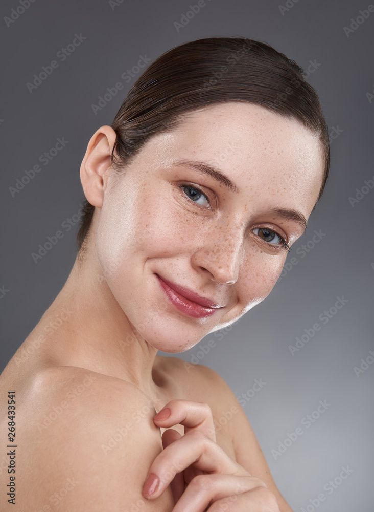 Beautiful smiling girl with freckles touching her shoulder Beautiful smiling girl with freckles touching her shoulder