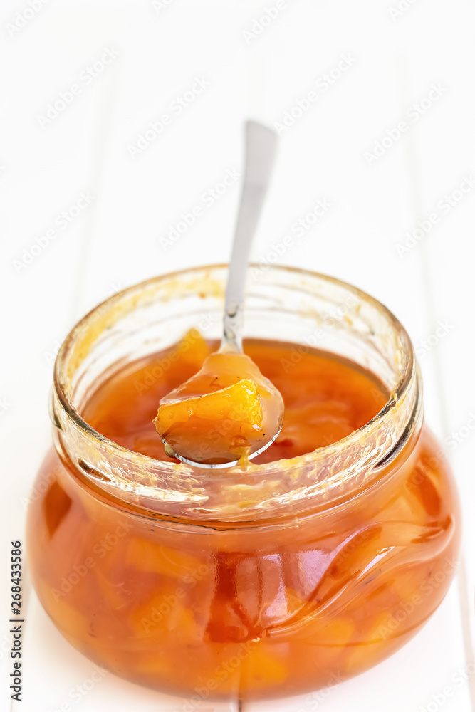 Homemade nectarine or peach jam confiture in glass jar and spoon on white wooden background. Selective focus. Copy space. Homemade nectarine or peach jam confiture in glass jar and spoon on white wooden background. Selective focus. Copy space.