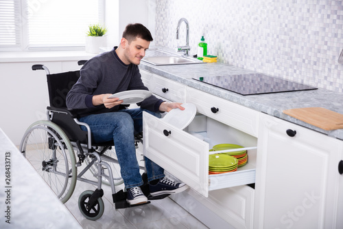 Disabled Man Sitting On Wheelchair Arranging Plates