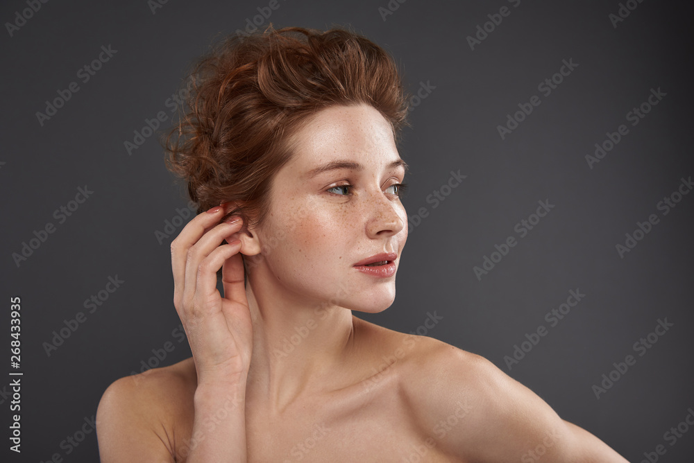Fototapeta premium Beautiful red-haired girl with natural makeup touching her ear