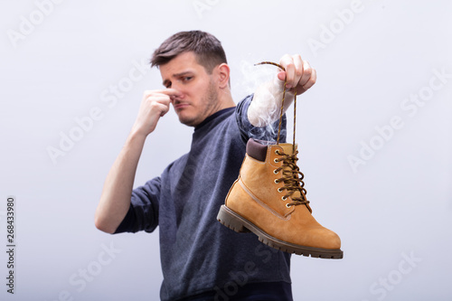 Man Covering His Nose While Holding Stinky Shoe photo