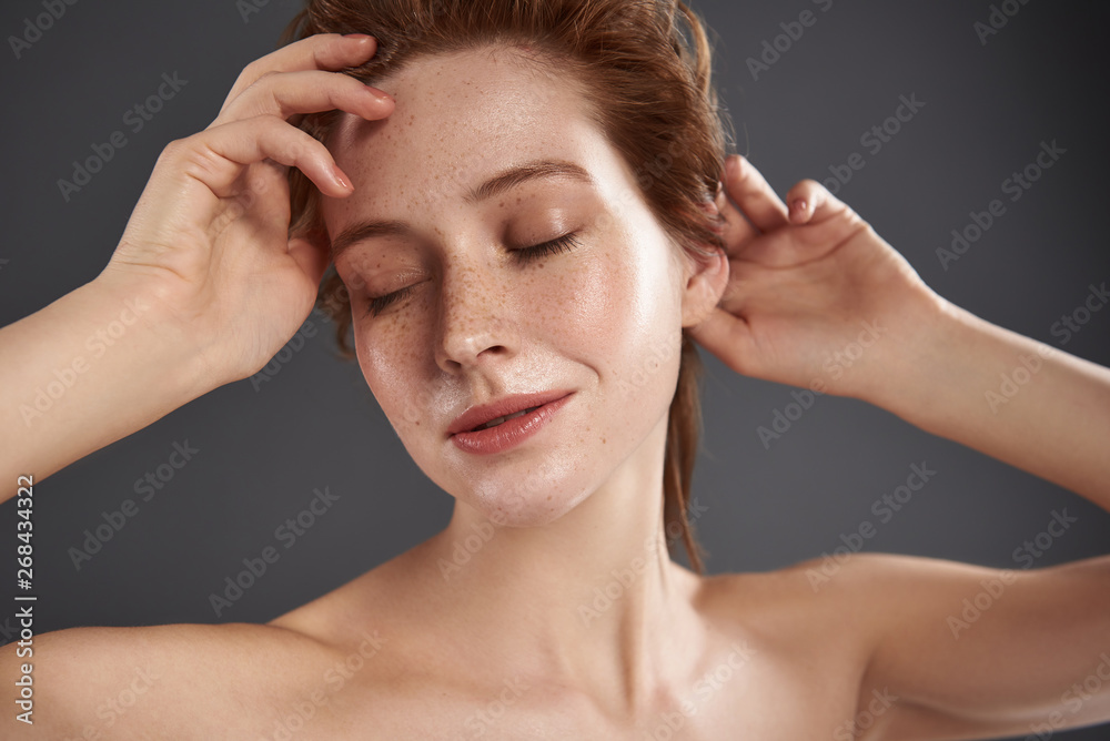 Beautiful red-haired girl with closed eyes keeping hands on her head Beautiful red-haired girl with closed eyes keeping hands on her head