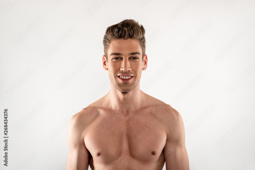 Attractive young man with perfect body standing against white background