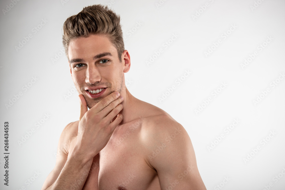 Attractive young man with stylish haircut touching his chin Attractive young man with stylish haircut touching his chin