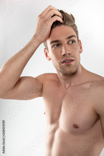 Handsome young man with perfect body touching his hair