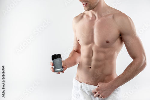 Young man with perfect muscular body holding antiperspirant