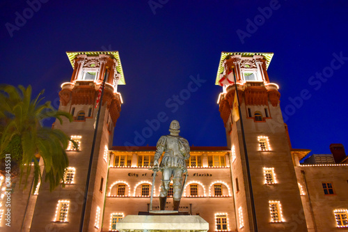 St. Augustine, Florida. January 26, 2019. Illuminated Lightner Museum and Henry Flager statue on blue night background in Florida's Historic Coast photo