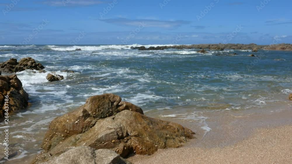 Waves lap on the shore at beach with rock in foreground. Slider shot. Waves lap on the shore at beach with rock in foreground. Slider shot.