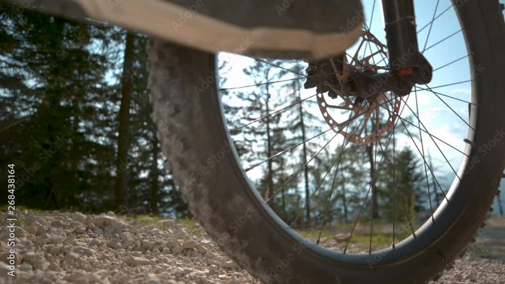 LENS FLARE, SLOW MOTION, CLOSE UP, LOW ANGLE: Unrecognizable athletic man brakes while riding bike down a gravel track. Cinematic shot of rocks flying as mountain cyclist rides down hill on sunny day LENS FLARE, SLOW MOTION, CLOSE UP, LOW ANGLE: Unrecognizable athletic man brakes while riding bike down a gravel track. Cinematic shot of rocks flying as mountain cyclist rides down hill on sunny day