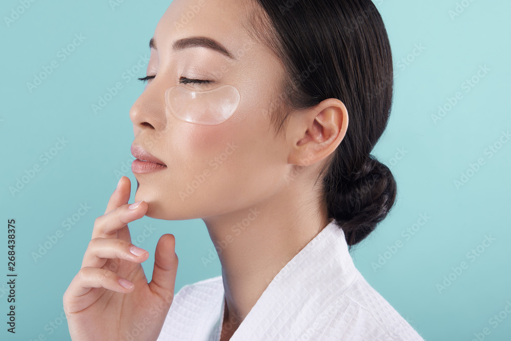 Close up of charming Asian lady with patches under eyes in studio Close up of charming Asian lady with patches under eyes in studio