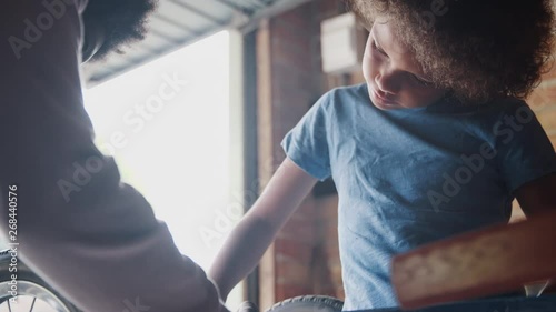Close up of pre teen boy standing at a workbench concentrating on screwing in a bolt while building a racing kart with his father, selective focus
