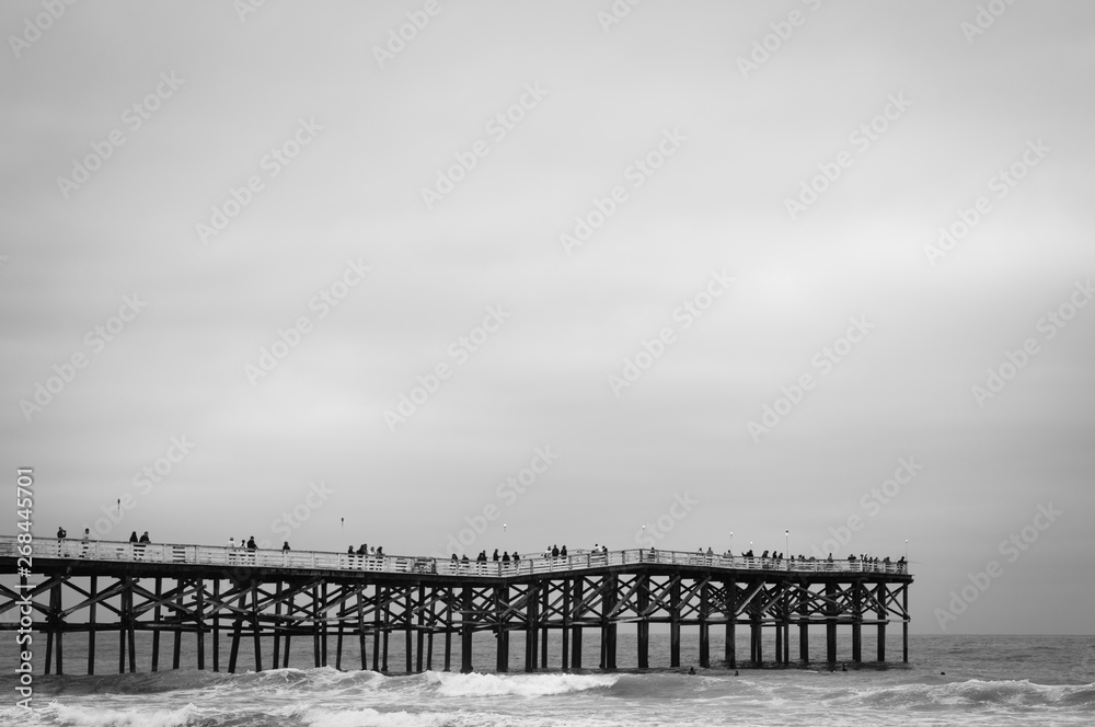 Waves in the Pacific Ocean and the pier in Pacific Beach on a cloudy evening, in San Diego, California