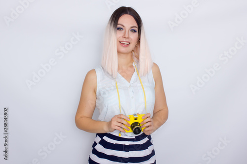 Blonde woman holding yellow retro camera