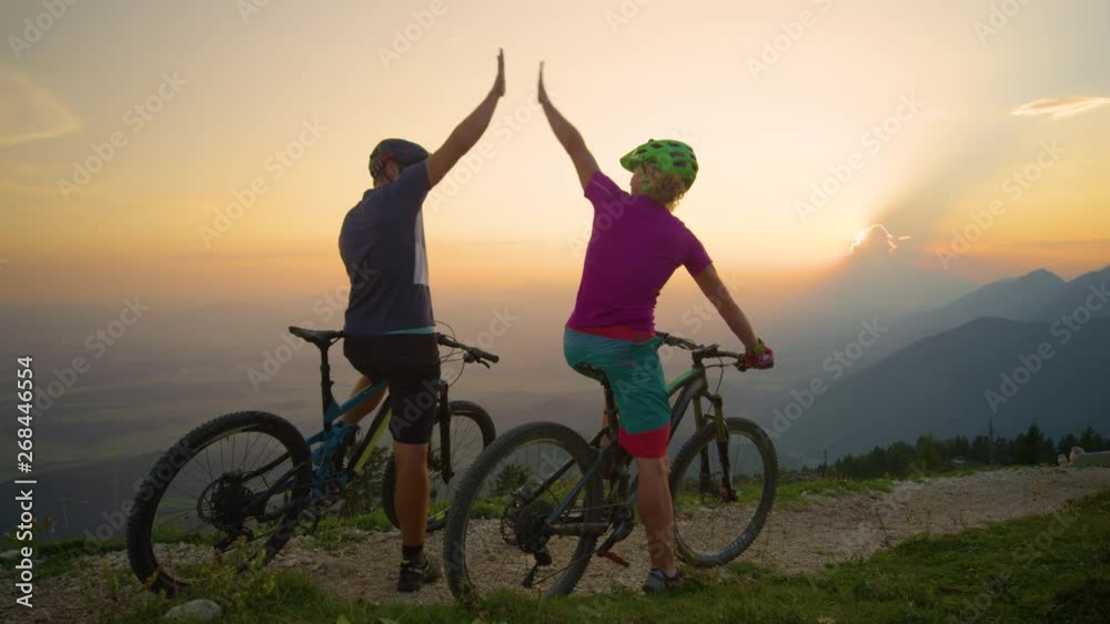 SLOW MOTION: Joyful young mountain bikers high five at sunset while sitting on their bicycles. Cheerful friends high five at sunrise before a cool cross country bicycle adventure in the mountains. SLOW MOTION: Joyful young mountain bikers high five at sunset while sitting on their bicycles. Cheerful friends high five at sunrise before a cool cross country bicycle adventure in the mountains.