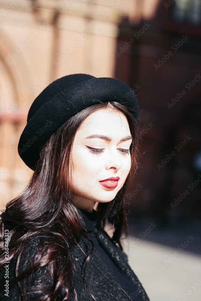 A girl in a black coat walks down the street A girl in a black coat walks down the street