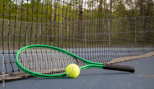 Close up of tennis ball and racket on court with net in the background  © Don Mroczkowski