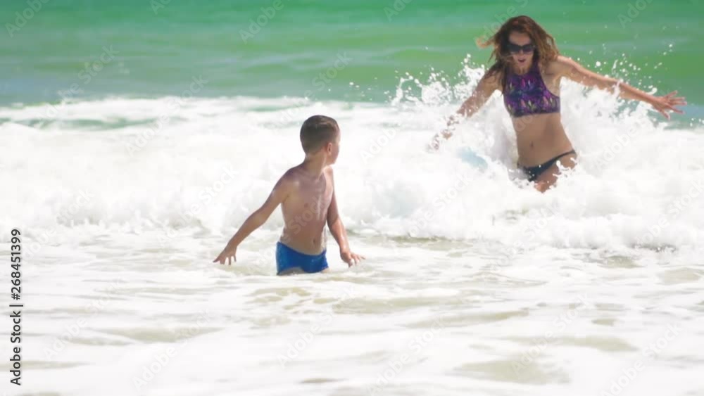 mother and son jump into the sea on the waves, rejoise, have fun. mother and son jump into the sea on the waves, rejoise, have fun.