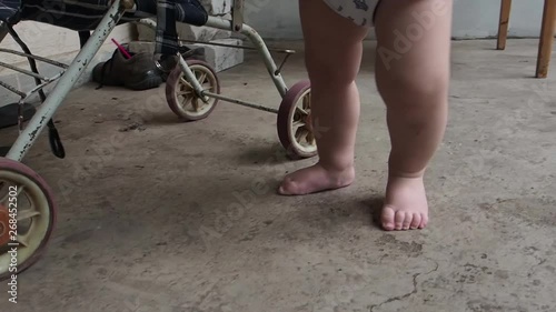 A blond-haired toddler plays with an old baby stroller