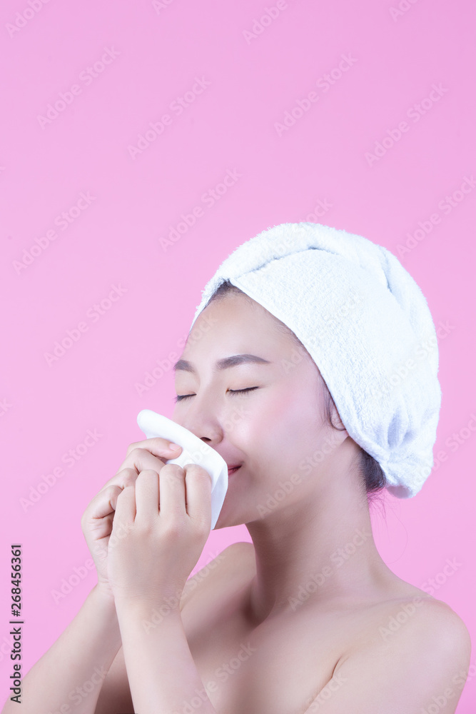 Asian beautiful woman wiping the face on a pink background, Cosmetology and Spa . Asian beautiful woman wiping the face on a pink background, Cosmetology and Spa .