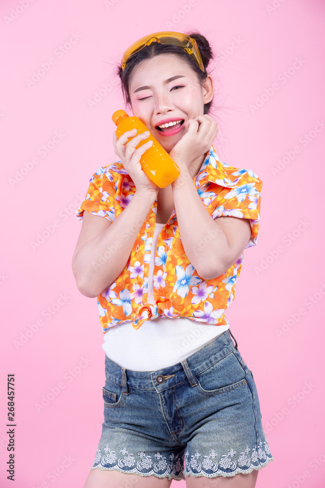 The girl holds a bottle of orange juice on a pink background. The girl holds a bottle of orange juice on a pink background.