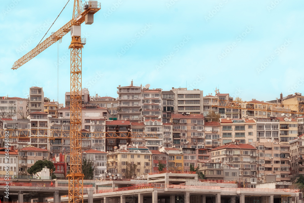 Crane and construction site on the background of a quarter of old residential buildings.