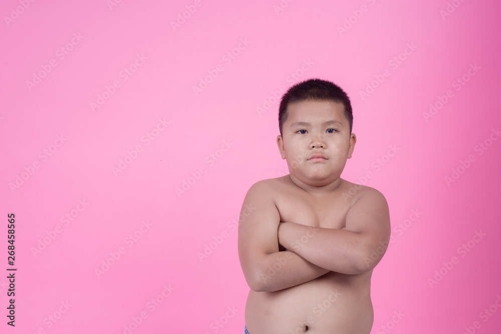 Obese boy who is overweight on a pink background.