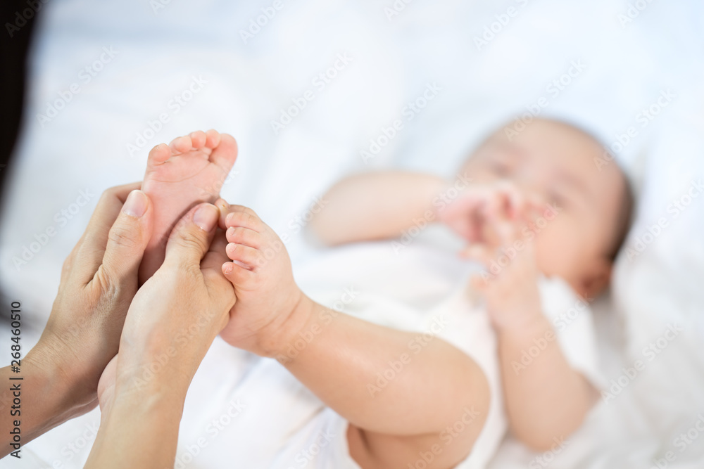 Asian baby happy in the room.Asian baby girl lying down on bed .Mothe hold foot baby. Asian baby happy in the room.Asian baby girl lying down on bed .Mothe hold foot baby.