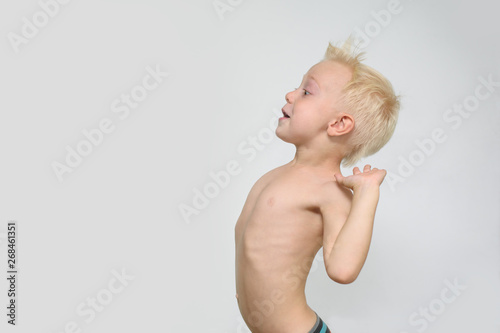 Surprised little blonde shirtless boy depicts a strong wind. Profile. White background. Summer concept