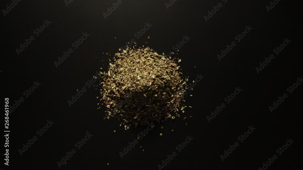 STOP MOTION: Dried basil leaves is piled up on the black table STOP MOTION: Dried basil leaves is piled up on the black table