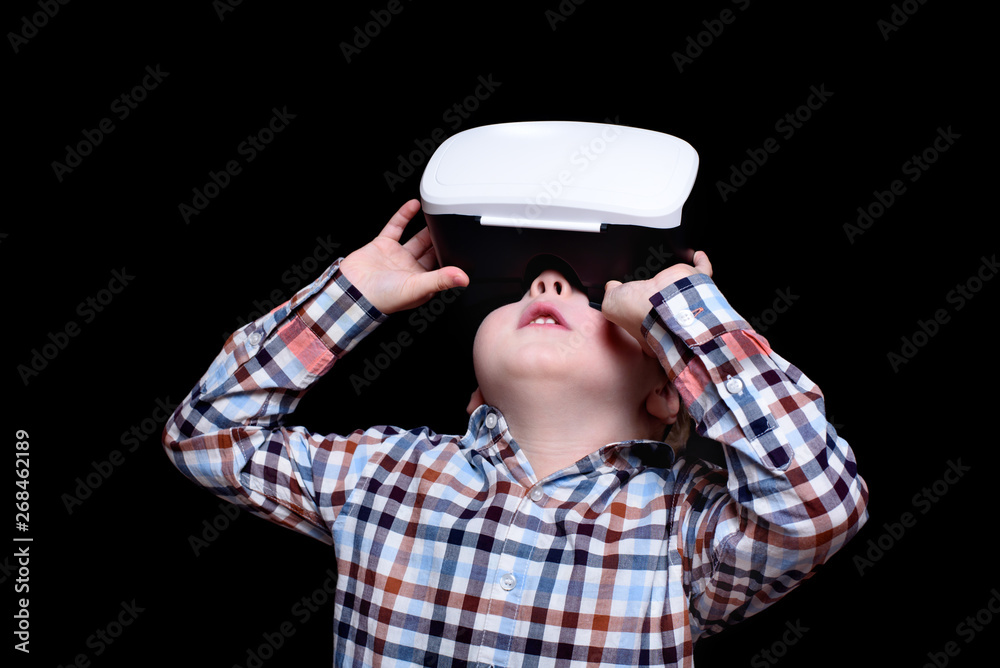 Little blond boy with glasses of virtual reality looks up. Plaid shirt. Black background Little blond boy with glasses of virtual reality looks up. Plaid shirt. Black background