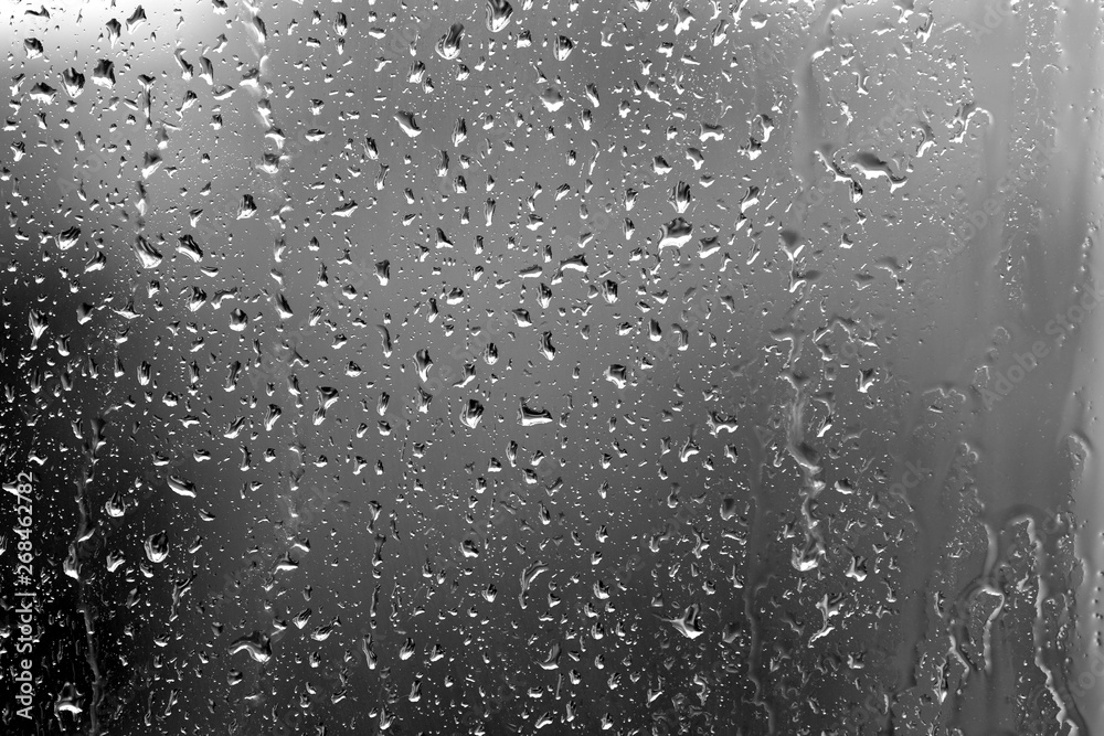 Raindrops on glass in rainy weather close up. Natural background black and white Raindrops on glass in rainy weather close up. Natural background black and white