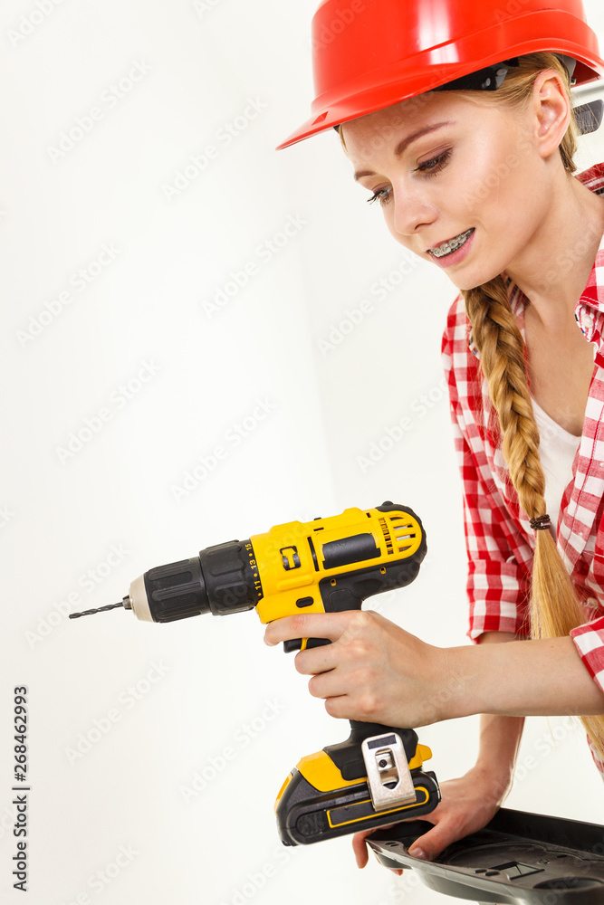 Woman using drill on ladder Woman using drill on ladder