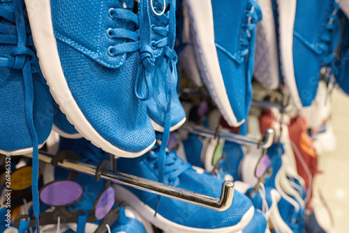 Men sneakers on hangers in a big department store.