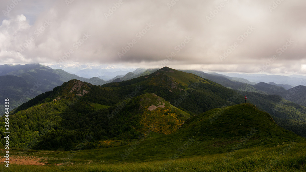 Mountains and hills covered with forests and alpine meadows under the very cloudy sky. Sunset. Mountains and hills covered with forests and alpine meadows under the very cloudy sky. Sunset.