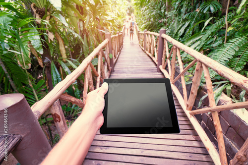 Fototapeta Naklejka Na Ścianę i Meble -  Traveling concept. Technology and adventure. Close up of hands holding tablet computer with copy space on screen in jungle.