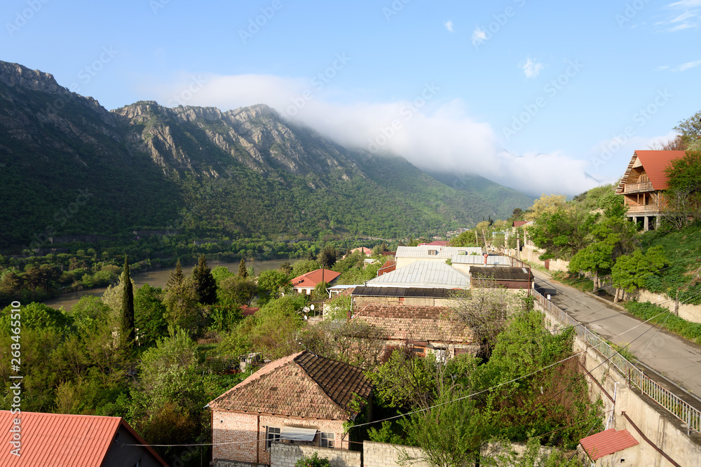 Top view of street of Mtskheta in morning. Tiled roofs, mountain and Kura River Top view of street of Mtskheta in morning. Tiled roofs, mountain and Kura River
