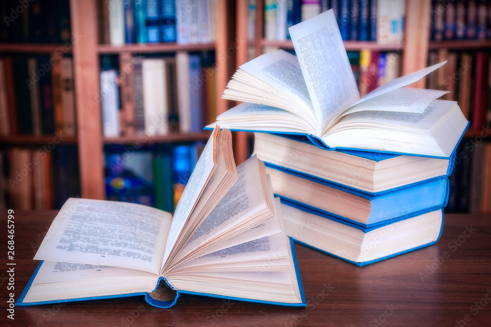 Book stack on wood desk and blurred bookshelf in the library room, education background, back to school concept Book stack on wood desk and blurred bookshelf in the library room, education background, back to school concept