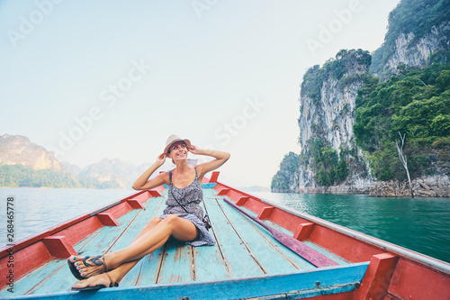Happy vacation in Thailand. Pretty young woman taking sailing Khao Sok National Park lake on traditional longtail boat.