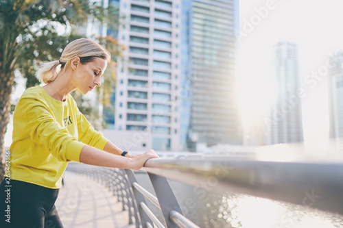 Heat and sport. After exercising. Tired young woman on the city embankment. photo