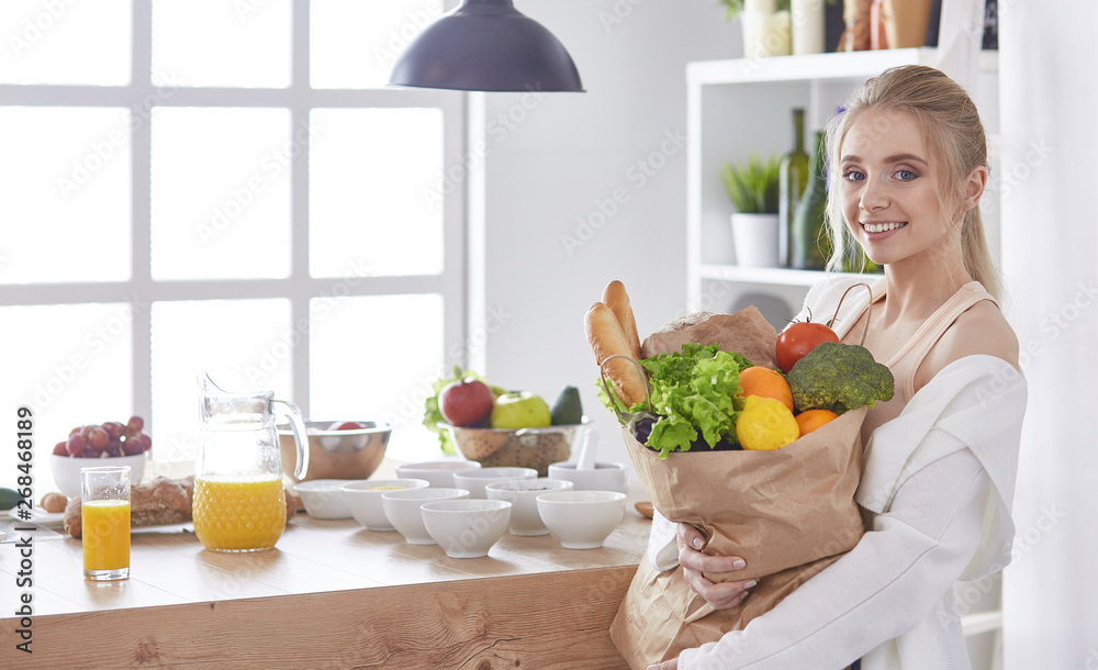 Young woman holding grocery shopping bag with vegetables Standi Young woman holding grocery shopping bag with vegetables Standi