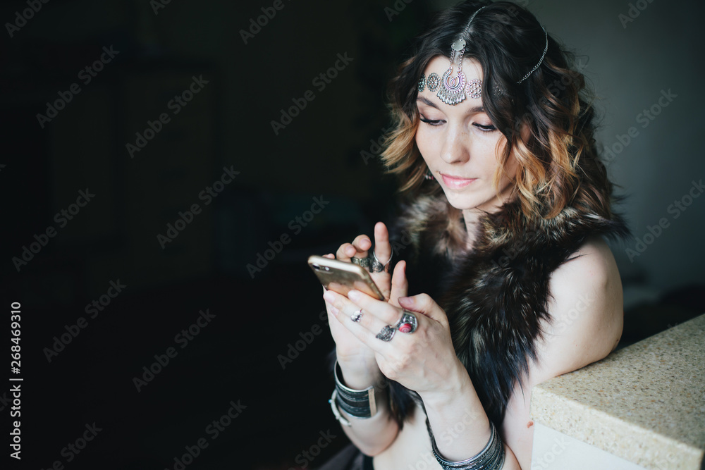 Beautiful fashion female tribal style wearing jewellery using cell phone