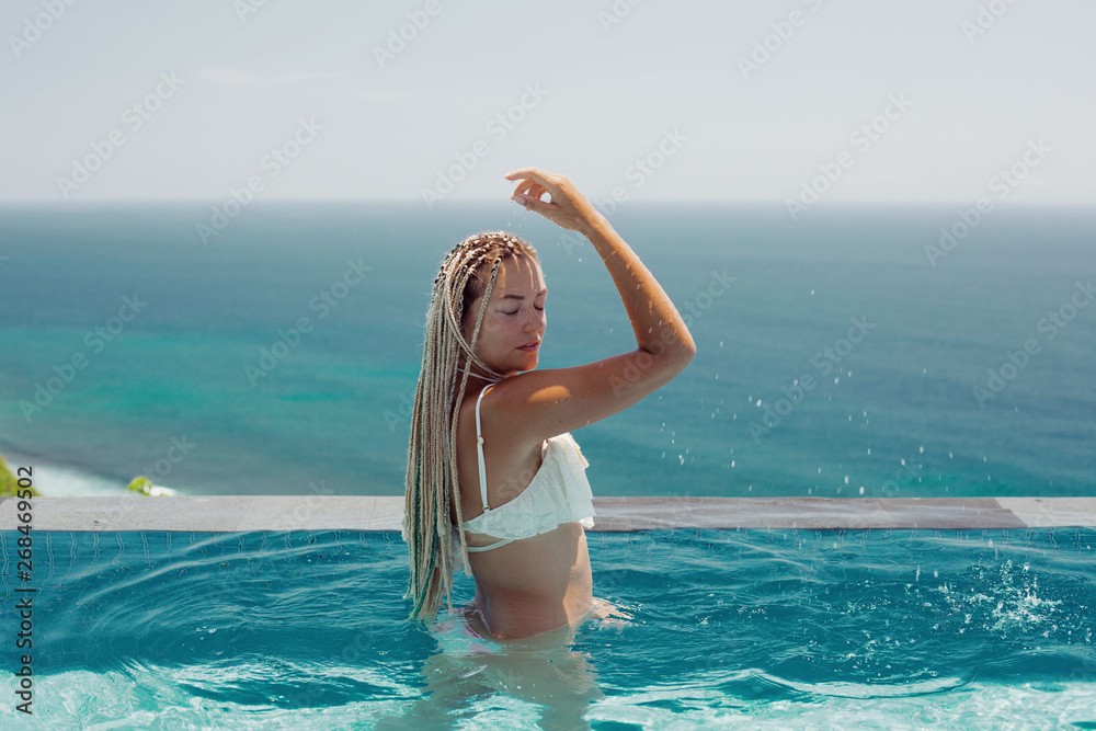 Woman enjoying in swimming pool with sea background view Woman enjoying in swimming pool with sea background view