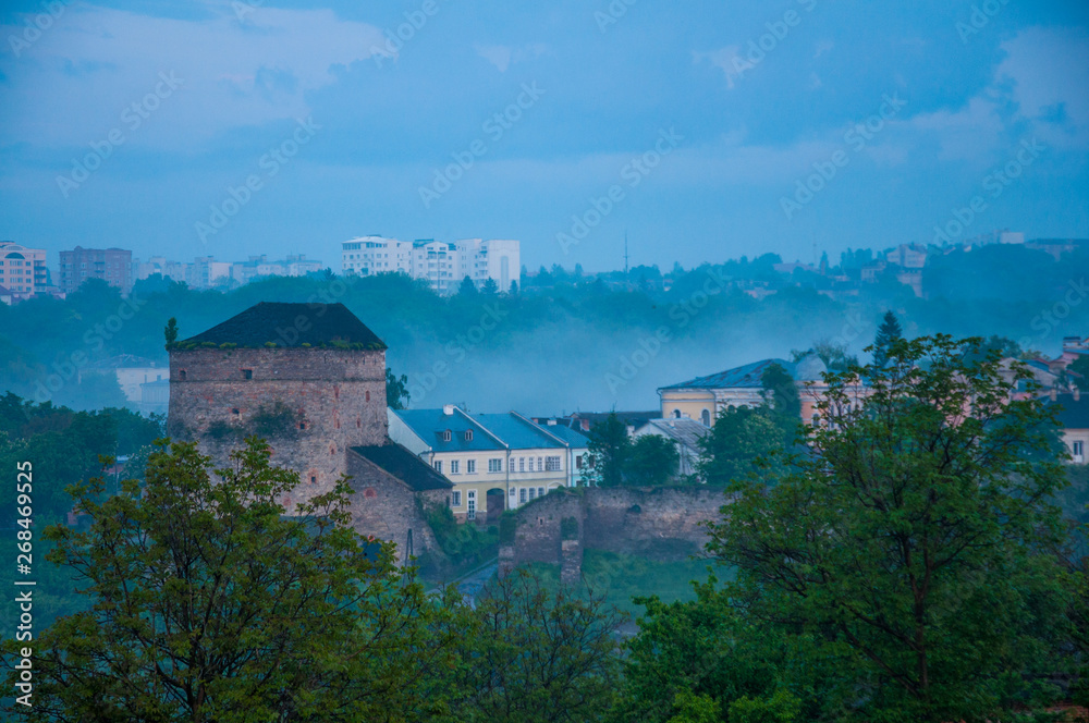 evening old city in the fog. Big stone tower. Twilight in Kamenetz-Podolsk. Low clouds