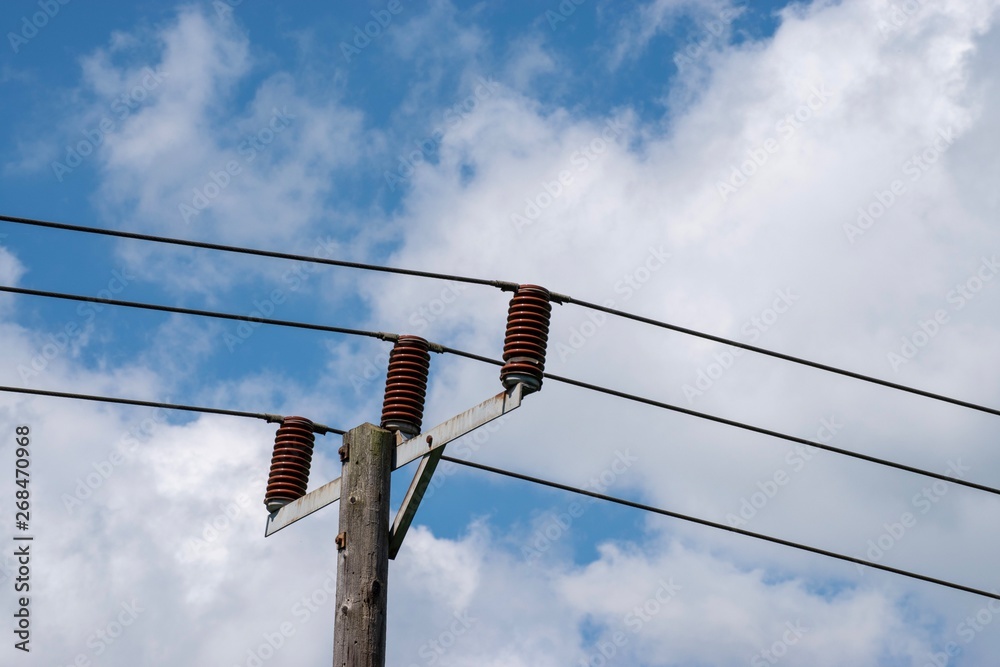 Power cables seen against a blue sky with white clouds