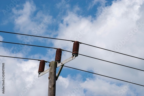 Obraz na płótnie Power cables seen against a blue sky with white clouds w salonie