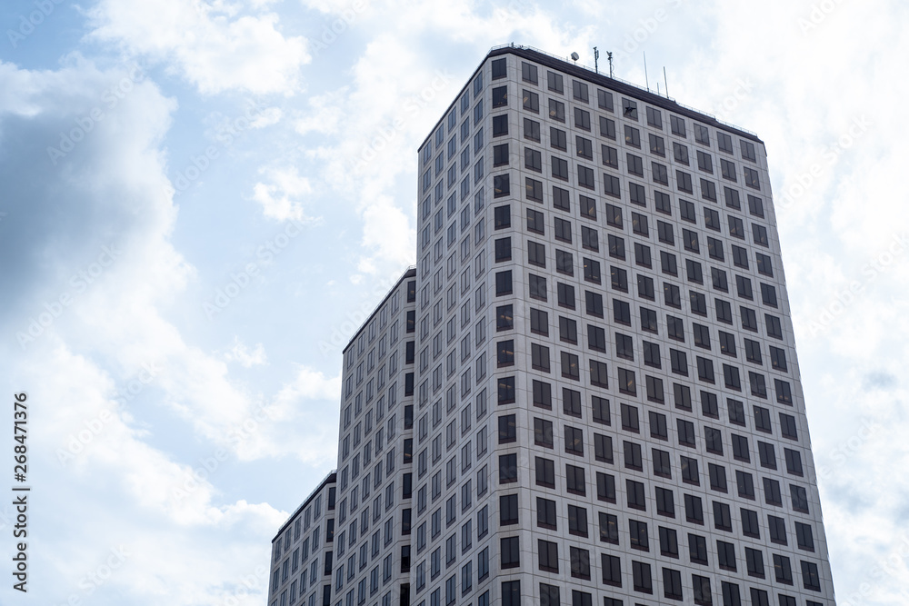 Low Angle Of Modern Glass Skyscraper Against Vivid Blue Sky with Clouds Low Angle Of Modern Glass Skyscraper Against Vivid Blue Sky with Clouds