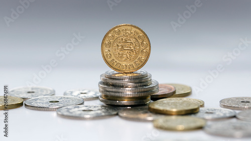 Photography Ten Kroner coin standing on a stack of mixed Danish coins with selective focus