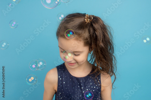 Beautiful little long hair girl playing with bubbles at a kinder playground.